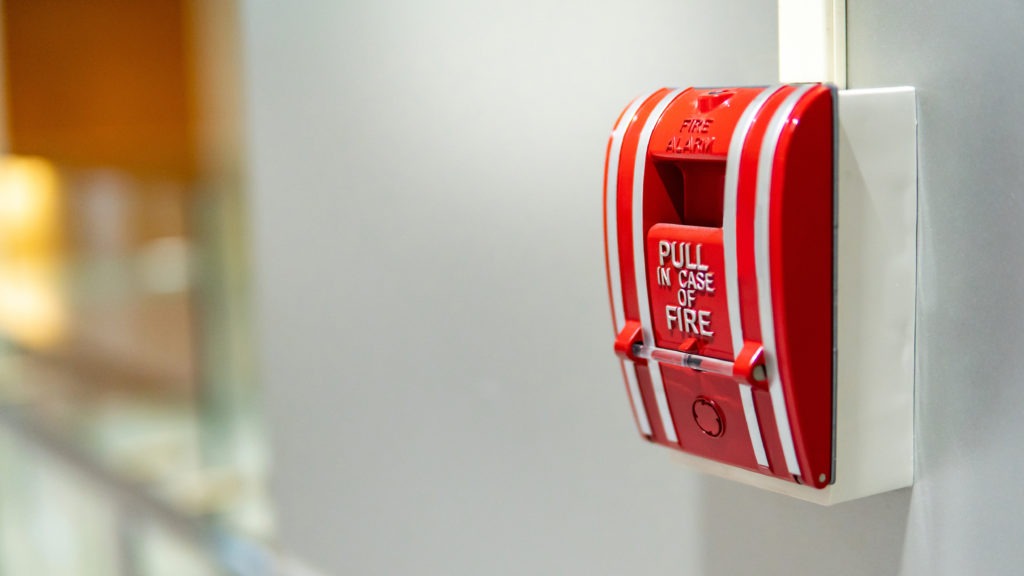 Fire safety: red fire alarm hangs on wall