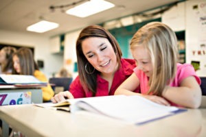 A teacher helps student girl study at school