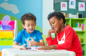 Two boys sit at a table reading while in school