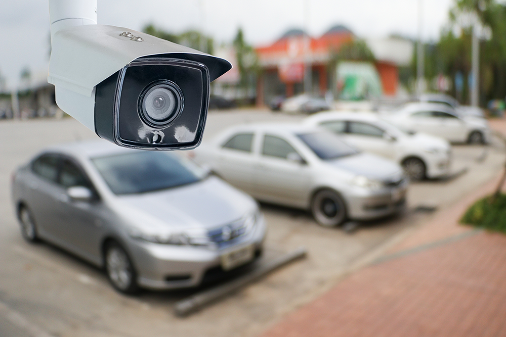 Blurred image of cars in a parking lot with video camera placed over it to demonstrate monitoring with video intercom systems